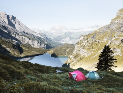 红色和灰色的帐篷在青草覆盖的山
